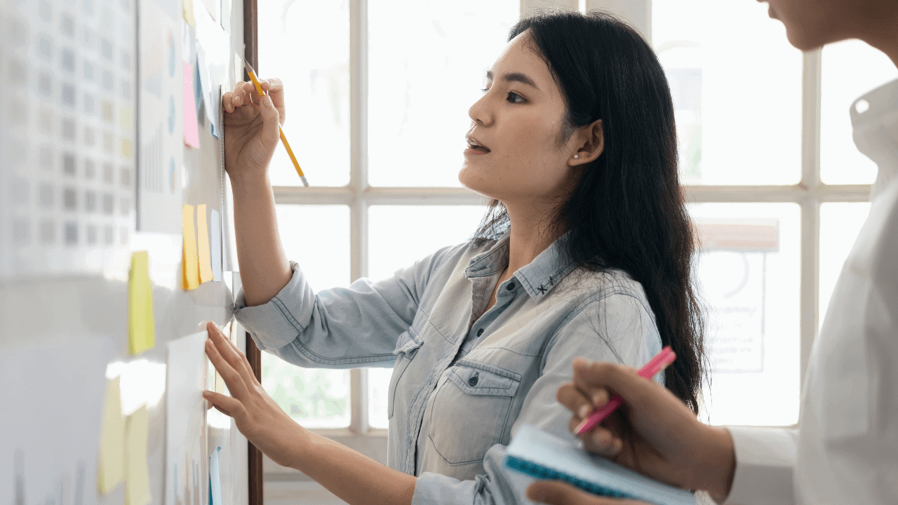 Young woman writing on dry erase board.