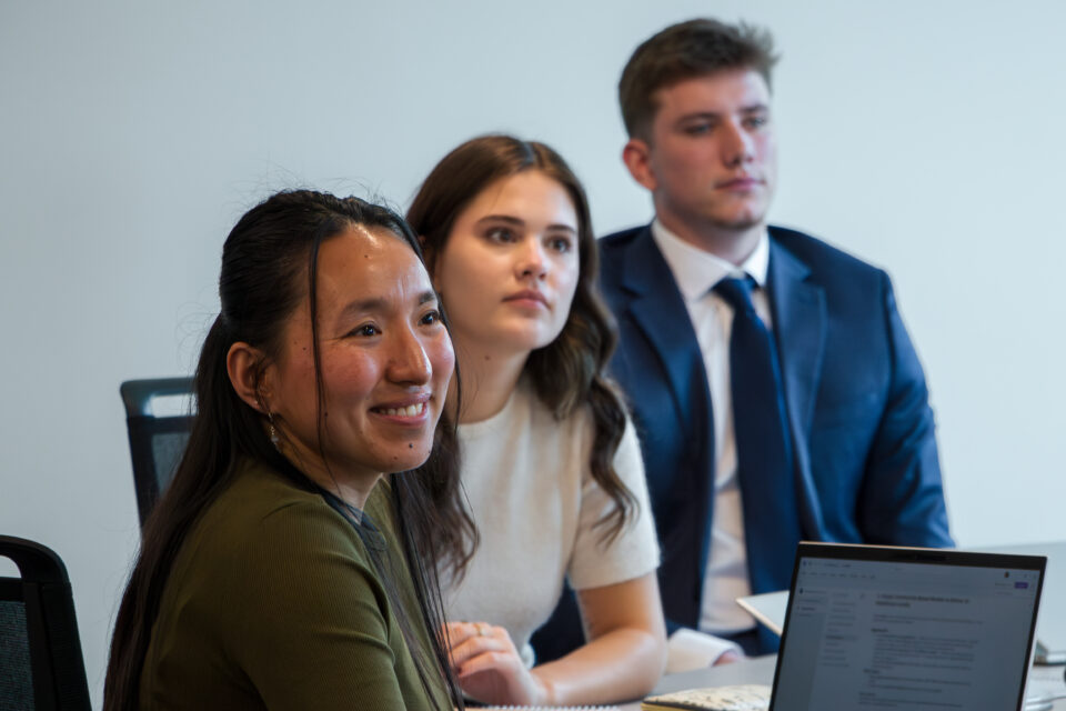 Three students listen to an instructor in a classroom setting. 