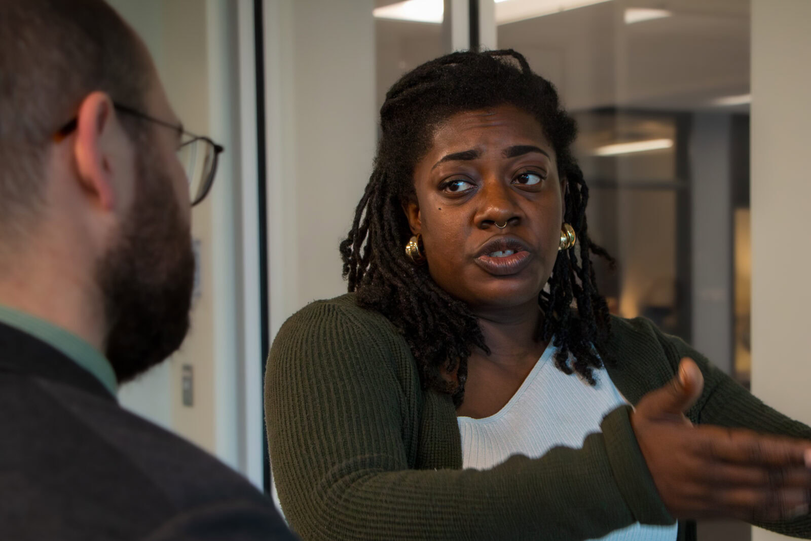 A female gesticulates during a presentation to a male listener that is seen from behind. 