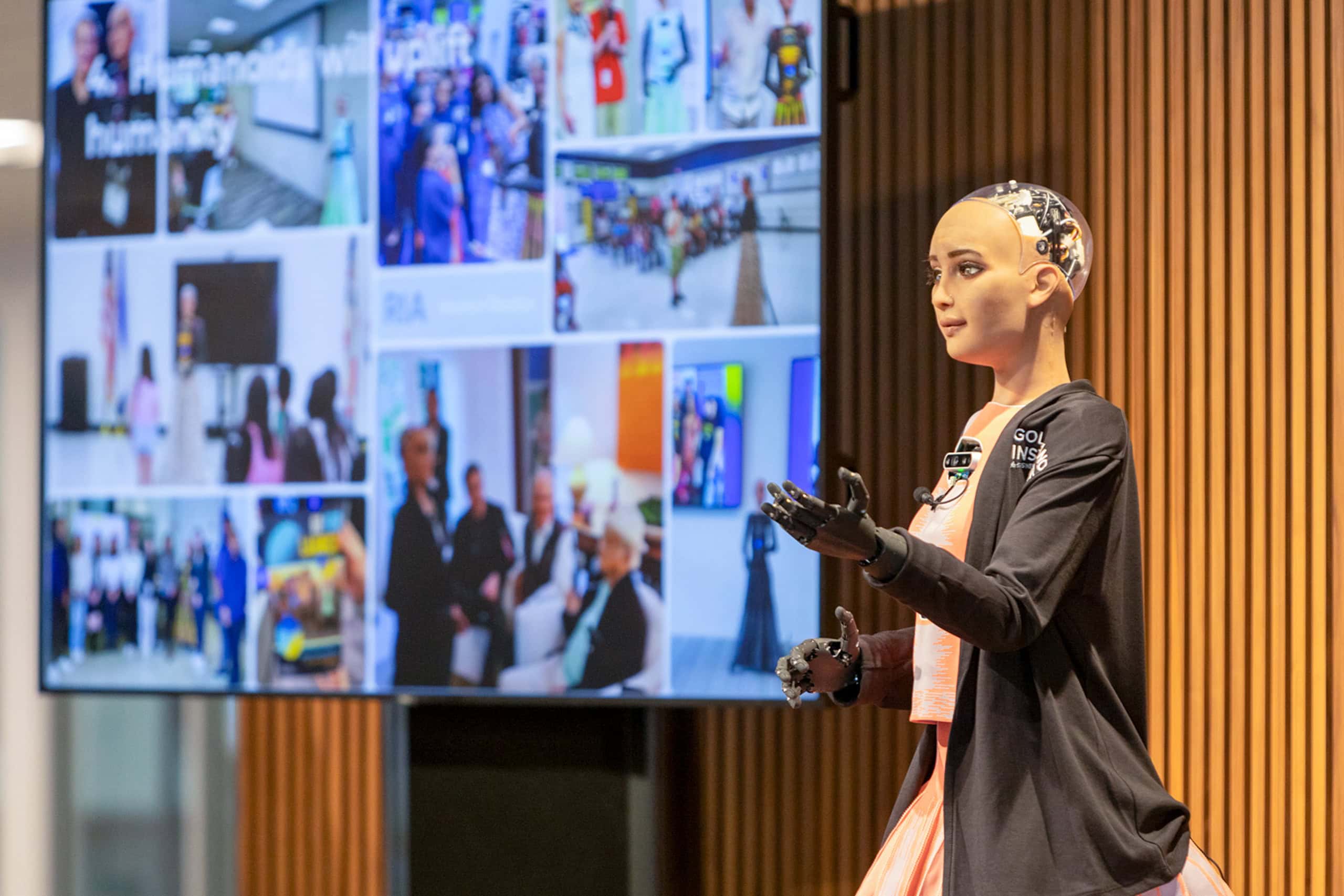 A humanoid robot called RIA, powered by AI, is pictured on a stage by a screen at Golisano Institute for Business & Entrepreneurship