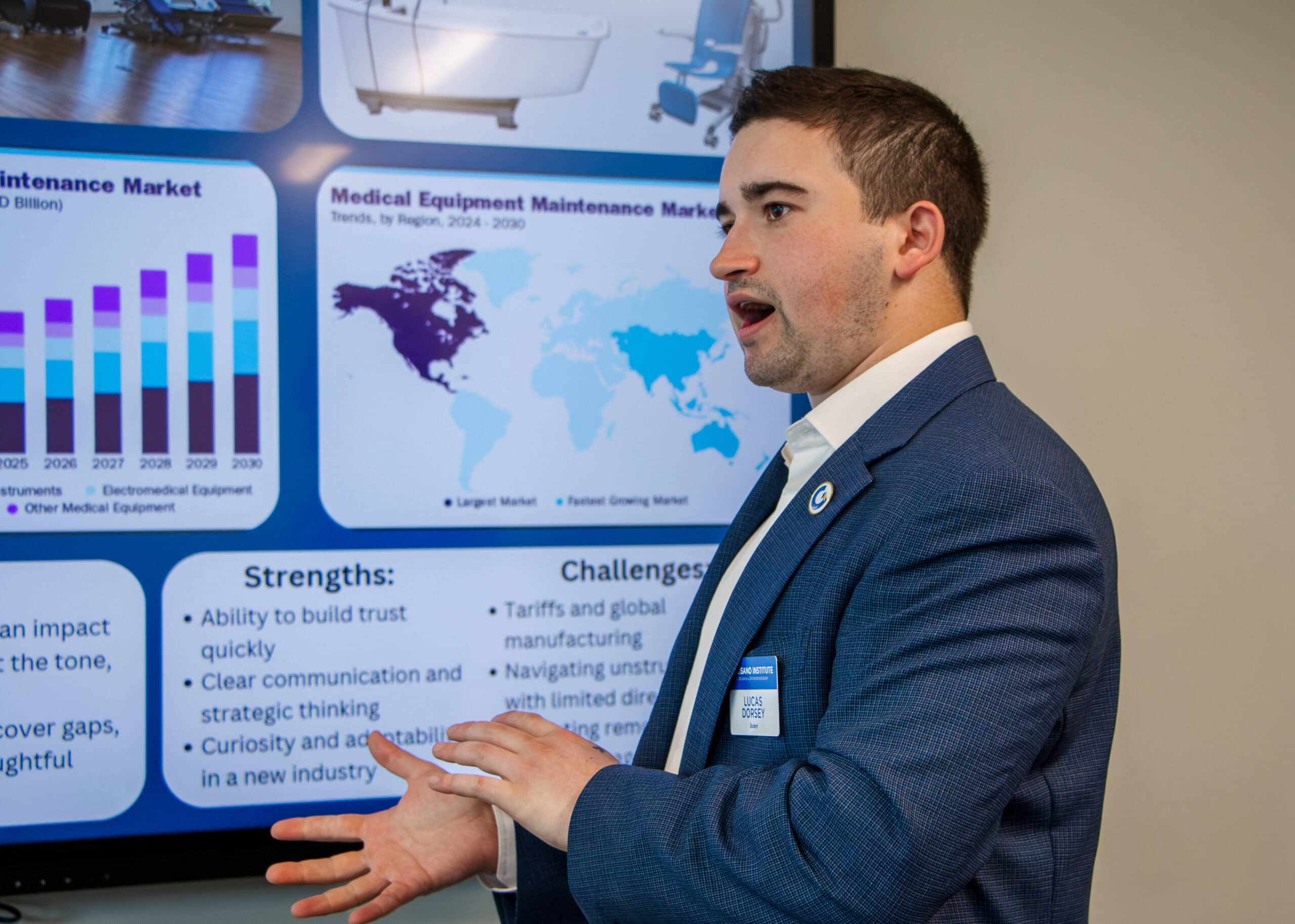 A male is seen before a slide on a screen during a presentation. 