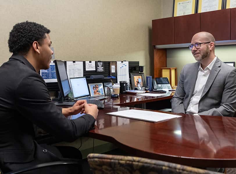 Student and instructor talking in an office.