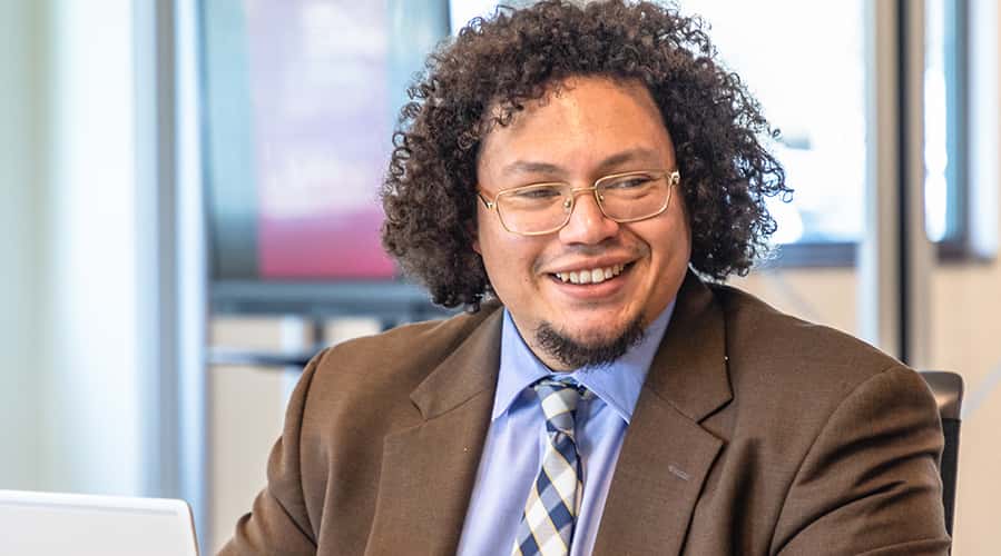 Student in business attire smiling in class.