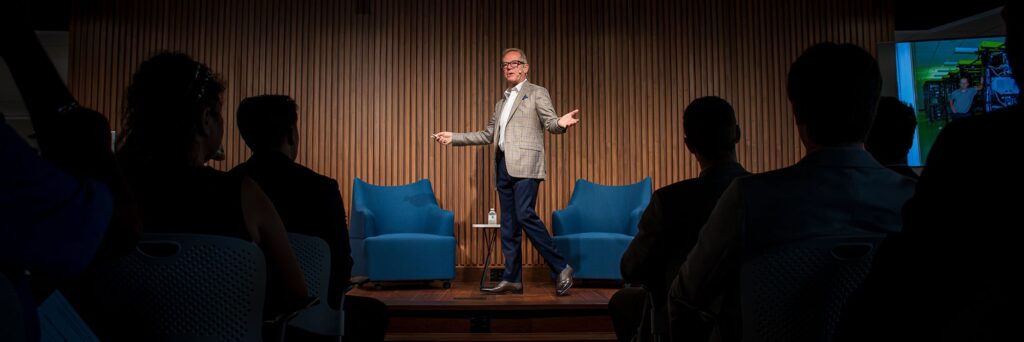Kevin Surace presenting on stage at Speaking from Experience with the audience in the foreground.