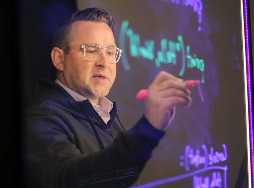 Instructor Mike Partridge writing on a see through screen.