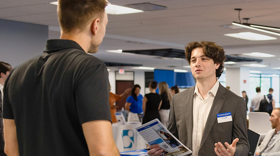 Student speaking with business partner at a networking event.