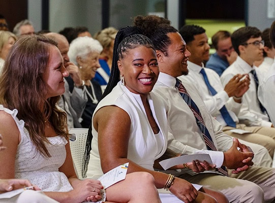 golisano-institute-story Golisano Institute graduates dressed in white, sitting in the forum.
