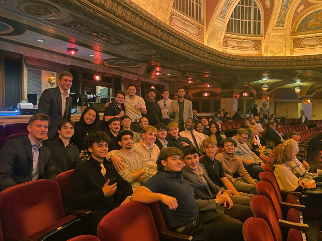 A group of people aged between 20 and 30 sitting together as a group in a historic theatre