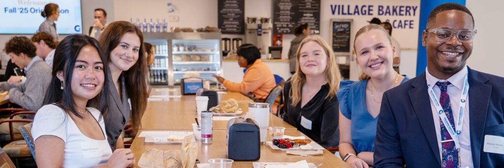 A group of students poses smiling while sitting at a table in the cafe.