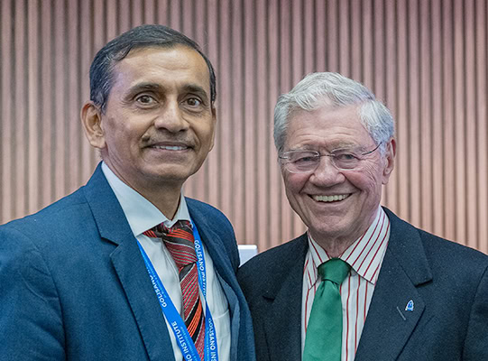 Two men in suits smiling and posing for a photograph.