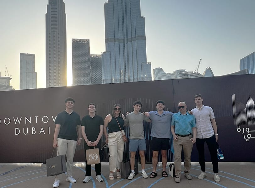 A group of students with a professor pose in front of the Burj Khalifa in Dubai.