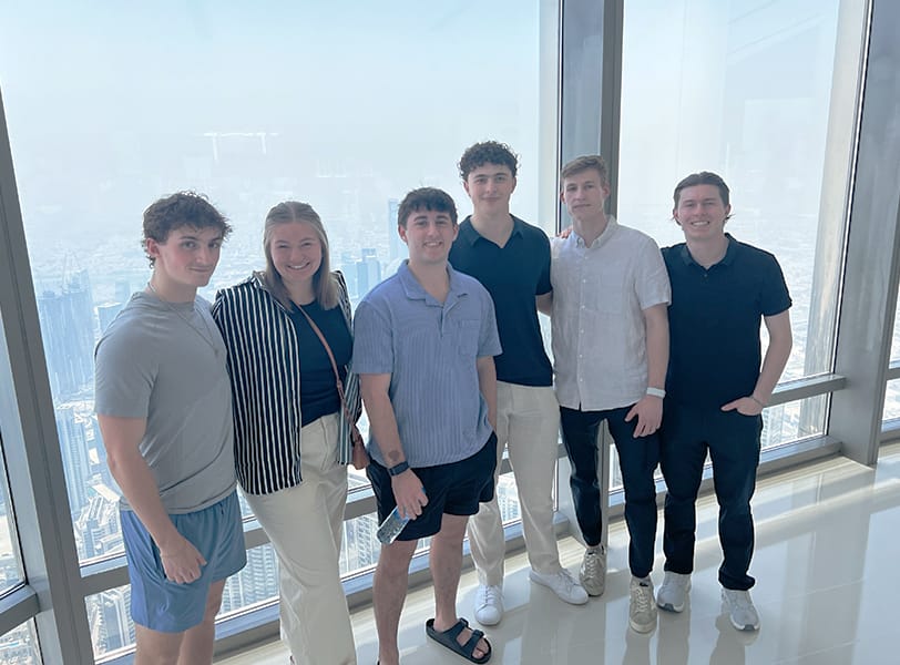 A group of students pose in front of a window high up in the Burj Khalifa in Dubai.