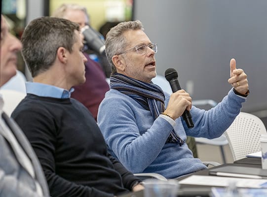 Man with a microphone sitting at a judges table.
