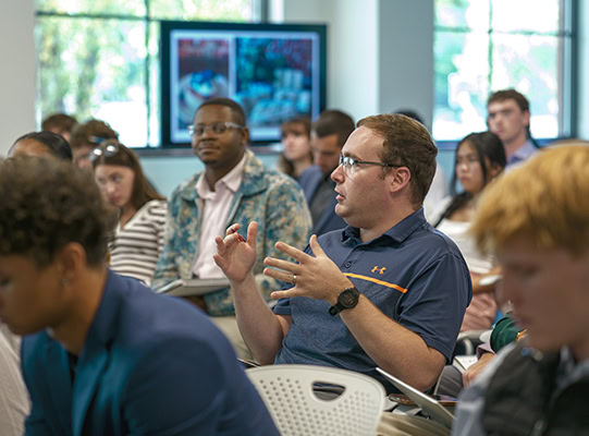 A student ask a question in the middle of a classroom.