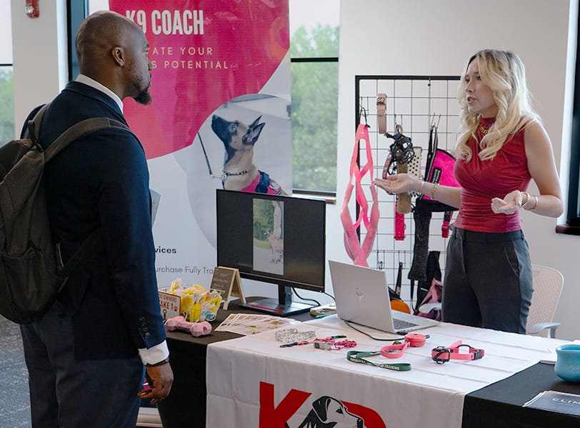 A female student presents at a booth during the Entrepreneurial Fair at Golisano Institute.