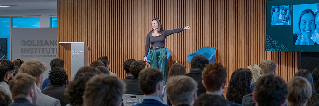 A woman presents to a crowded Forum at a Speaking from Experience event.