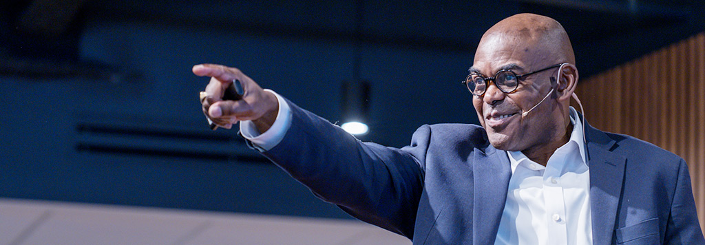 A speaker points to members of the audience.