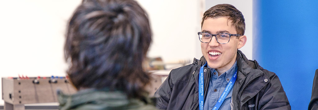 Two students in conversation near a foosball table.