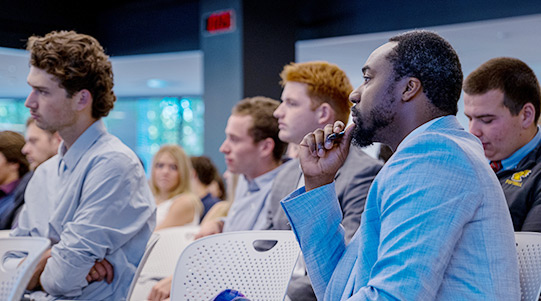 Students listen to a presentation in the forum