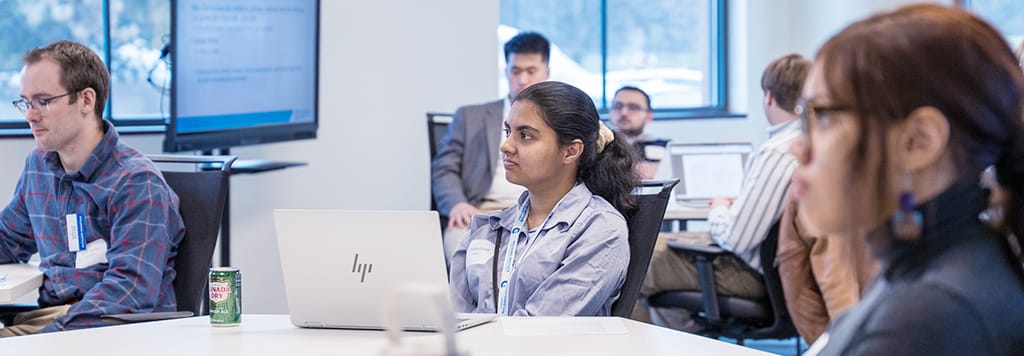 Students with laptops listening to a lecture in class