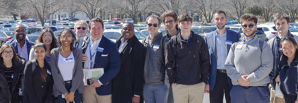 A group shot of students and instructors standing outside in a parking lot on a sunny day.