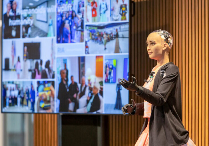 A humanoid robot called RIA, powered by AI, is pictured on a stage by a screen at Golisano Institute for Business & Entrepreneurship
